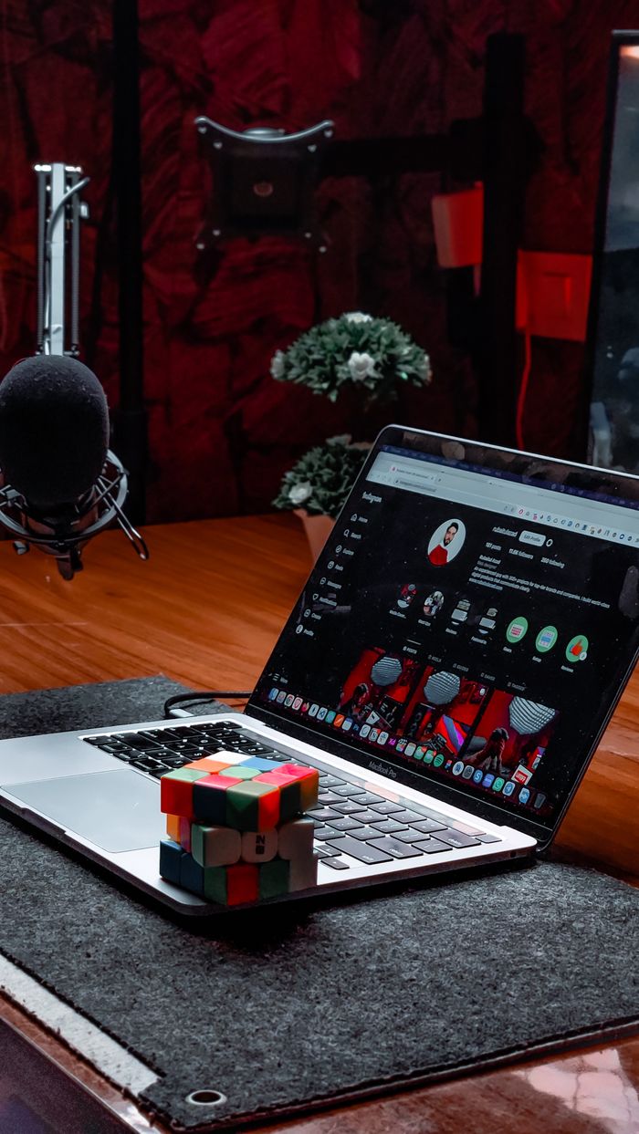 Modern workspace featuring a laptop, Rubik's Cube, and podcast microphone in a studio setting.